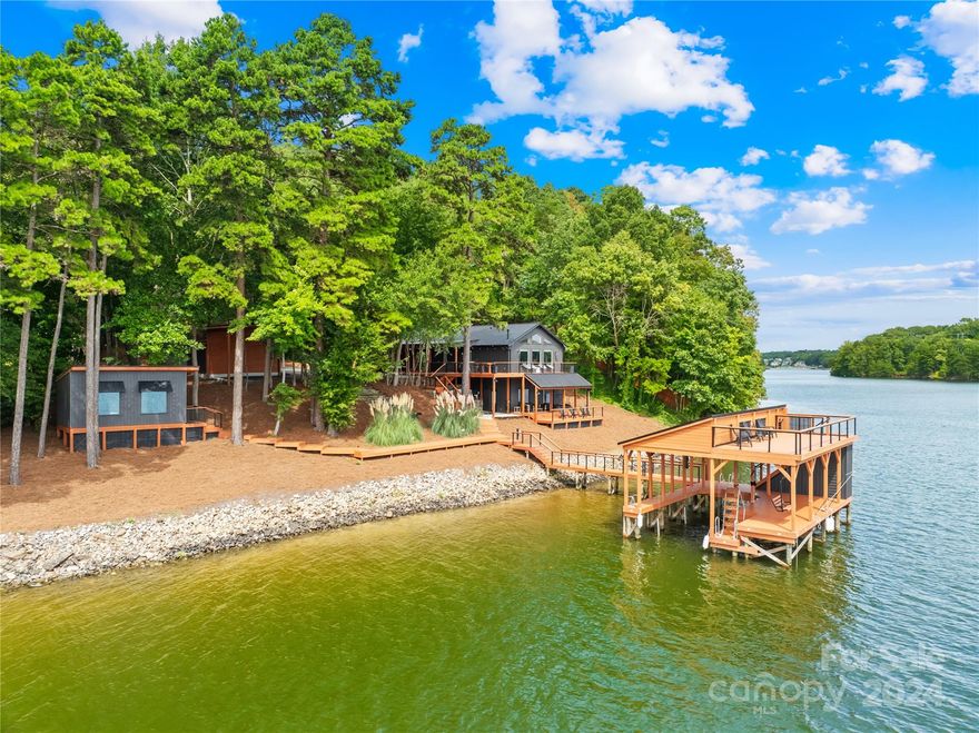 With its ONE OF A KIND $200,000 dock and boat lift, this waterfront Oasis is a must see. The fully furnished 3-bedroom, 2-bathroom home boasts 228' feet of shoreline with a stunning primary bedroom suite offering sweeping lake views. Enjoy a life of luxury on the large custom built dock with an upper deck sitting area, storage closet, a cable boat lift accommodating up to 10,000 lbs, and two additional mooring areas. The retreat includes two separate buildings for extra sleeping areas, a detached gym with panoramic water views, and a versatile building perfect for a garage, game room, or yoga studio. With freshly stained decks, beautifully landscaped grounds, and a gated, fairytale-like driveway, this short-term vacation rental is a true gem. The home also features an updated kitchen and bathrooms, a large covered RV parking area, and extra-large covered parking. The covered dock in one-of-a-kind with an upper half deck and lower under stairs storage closet. This is an operational STR.