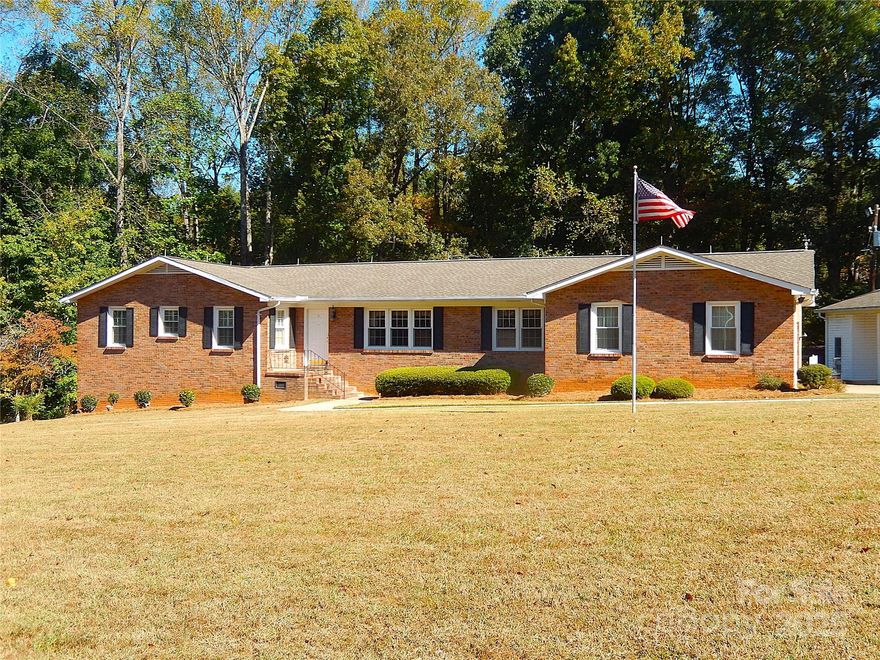 Located minutes away from Ballantyne and Blakeney in Indian Land, this one-owner full brick home has been well-loved since it was completed in 1973.  A classic home with an eat-in kitchen w/granite countertops & tons of cabinetry, a formal dining room & living room, and a comfortable den with gas log fireplace and a full masonry fireplace.  There are two spacious secondary bedrooms with an updated Jack & Jill bath.  The primary bedroom has a walk-in closet and the primary bath has double sinks and a pocket door to separate the vanity area from the toilet and bathtub/shower.   Gleaming hardwood floors in the kitchen, den, hallway, & both secondary bedrooms.  The primary bedroom, dining room, & formal living room are carpeted.   The den, both baths, and all bedrooms have plantation shutters on the windows.  The 810 sf basement has two partially finished rooms (drywall/ceilings) with carpet removed.  The rest of the basement is ready to be finished off, even including a rough-plumbed bath.  The basement is not being included in our HLA due to flooring, but is heated and cooled, and could realistically add another whole living area if finished.  Out back, there is a deck with a door directly into the den.   There is an attached 2-car finished garage with extra storage space leading into either the kitchen or the mudroom, and an oversized 2-car carport that was used for RV parking.  The carport also has an attached wired workshop!  Two additional storage buildings are located behind the carport.    This lot is FIVE acres, with the back portion being fully wooded.  The house sits up on the tallest portion of the lot.  A full home inspection was done on October 15, and the report is available from your agent or upon request.  As to be expected with a 50+ year old home, there are some repairs needed, and the property is priced accordingly.   The listing agent is also the executor of the estate.  No probate court approval is necessary for contract approval.  The home is livable as it is, but the new owner may choose to do some repairs and cosmetic updating.  The fridge is new in 2025.  The washer and dryer (included) are also recent (2019).  Other appliances are older, but still in fine working condition.   SOLD AS IS.  No repairs will be done.   Although we are not required to disclose this, no one ever died in the home.  You do not want to miss this opportunity to live so close to shopping, dining, and entertaining, with no HOA, and with the lower SC taxes!  This has never been a house.  It was always a very happy home!