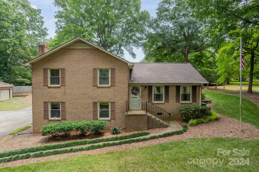 PRICE IMPROVEMENT! Outdoor living at its best from the beautifully landscaped yard, inviting brick patio, multiple sitting areas, garages & storage buildings, this property is truly one of a kind. This lovely home is nestled on .71 acres with no HOA but in close proximity to shopping, dining & entertainment. When you step inside, there are multiple areas for living & entertaining. On the lower level is an inviting den w/ stone fireplace (sold as-is, gas not connected), a bedroom/office/flex room, laundry area w/ built in cabinets, & a bathroom. Venture up a few steps to the main level to the kitchen with stainless steel appliances, formal living room, dining area, & inviting sunroom. On the upper level are 2 bedrooms, the primary bedroom, & a full bath with a soaking tub/shower & vanity w/ granite countertops. Back outside is a large detached garage with electricity, & a workshop. In addition to this are 3 other storage buildings. Garage, detached buildings, & grill are sold as-is.