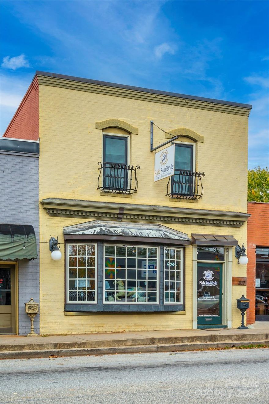 Located in the bustling downtown of Landrum, SC, this historic building features an open retail space on the street level, complete with exposed brick walls and concrete floors. The upstairs boasts a remarkable two-bedroom, two-bathroom apartment adorned with old heart pine flooring, alongside a full kitchen, dining, and living areas. Additionally, there is a covered porch at the back with stairs descending to the alley below. This offers an excellent live/work opportunity, enabling you to live upstairs and run a business on the main level. Alternatively, both units could serve as superb rental properties.