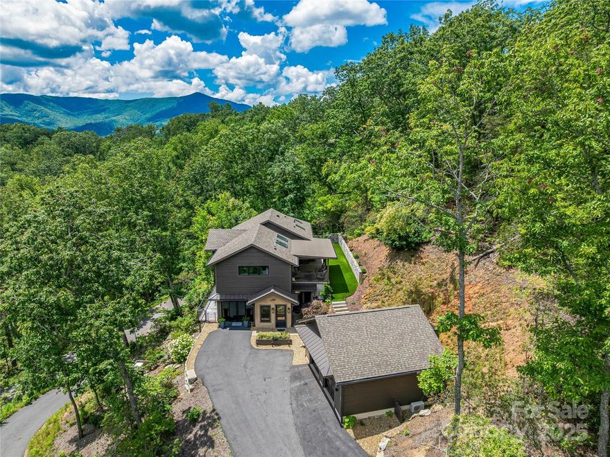 Tucked into the treetops just minutes from downtown Black Mountain, this luxury mountain retreat offers serenity, sophistication & sweeping year-round mountain views. Designed to bring the outdoors in, the main level features an open-concept great room & chef’s kitchen drenched in natural light, flowing seamlessly to a private covered porch—your front-row seat to every season. The primary suite offers privacy & its own deck escape, while the lower level creates space for everyone w/2 bedrooms, a den & a flexible bonus room complete w/Murphy bed & private entrances—ideal for guests or multi-generational living. An enclosed sunroom brings the outside in, perfect for quiet mornings or creative inspiration. The oversized 2 car detached garage is heated/cooled & ready for the future w/dual EV charging stations, smart-home technology & STR allowed. The home can be offered as a turnkey mountain retreat—Black Mountain at its finest, whether your primary, second home, or vacation rental.