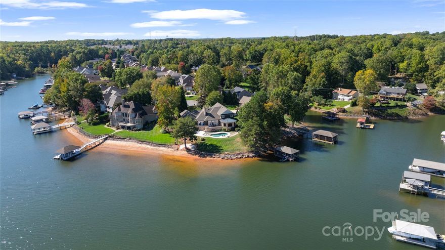 Nestled on the Western shore of Lake Norman, 2514 Smith Harbour Drive offers an extraordinary blend of luxury, comfort, and resort-style living. Designed to take full advantage of its big water views, this Nantucket-inspired home is filled with natural light, where a wall of French doors opens to a sweeping terrace overlooking the lake and backyard oasis. Inside, the open layout showcases a warm and inviting great room with a double-sided fireplace, flowing into the formal dining room. The updated chef’s kitchen is complete with a built-in refrigerator, a gas cooktop, a large movable island, and ample storage. The main living spaces connect seamlessly to the covered screened porch, featuring a fully equipped outdoor kitchen and kegerator, which creates the perfect setting for entertaining family and friends year-round. The gorgeous primary suite is a true retreat, featuring custom built-in bookshelves, a spa-inspired updated bath, and peaceful lake views. Three additional ensuite bedrooms, a private office, and two laundry rooms provide flexibility and convenience for today’s lifestyle. Step outside to enjoy your very own resort: a sparkling pool, private sandy beach, fenced yard, and a covered dock that makes lake life effortless. The property also features a versatile workshop integrated with a separate entrance, offering space for hobbies, storage, or creative projects. Every detail of this home has been thoughtfully designed to blend elegance with function — delivering an unmatched waterfront lifestyle on Lake Norman.