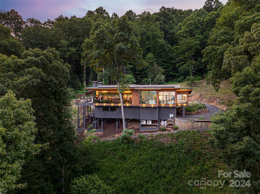 Discover an exceptional Asheville home nestled in the Blue Ridge mountains, seamlessly harmonizing with nature. Built into solid granite, this residence unites modern convenience with elegance. As clouds drift from Craven Gap, they pass through the “Cloud House”, where heaven and earth merge in perfect unity. Experience mesmerizing bird-watching just steps from the Blue Ridge Parkway. All of the cabinets and woodwork were meticulously custom-made on-site, using locally sourced wood. This eco-friendly home boasts solar panels, catering to most energy needs including water heating. The outdoor dining area includes a jacuzzi and fireplace, perfect for entertaining. This exceptional home has everything you could ever need to connect you to nature and allow you to embrace mountain living at its finest.