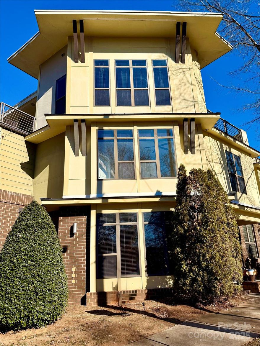 Urban sophistication meets unbeatable outdoor living in this corner townhome located in the heart of NoDa. Situated in the Steel Gardens community and overlooking North Charlotte Park, this 3-bedroom, 2.5-bath residence offers a rare combination of privacy, light-filled interiors, and an expansive rooftop terrace ideal for entertaining or relaxing above the city. The main level features hardwood flooring and an open-concept layout anchored by a stylish kitchen with granite countertops, oversized island,  Snowbound cabinetry, and stainless-steel appliances. Large windows fill the living and dining areas with natural light and open directly to a private, fenced rear patio—perfect for grilling or casual outdoor dining. Also – love the “Rocking Chair” front entrance patio. The second level includes two generously sized bedrooms, including one with an oversized walk-in closet, a shared bath with dual vanities, and a conveniently located laundry area. The entire third floor is dedicated to the primary suite, highlighted by vaulted 14-foot ceilings, abundant windows, a full bath, and direct access to the impressive rooftop terrace offering skyline views and endless entertaining potential. HOA fee includes water, sewer, trash, internet, cable, landscaping, and exterior maintenance. Enjoy walkable access to NoDa’s acclaimed dining, breweries, live music venues, boutiques, the light rail, and nearby green spaces, playground, and dog park. A rare opportunity to own a corner unit with exceptional outdoor living in one of Charlotte’s most dynamic neighborhoods. Overall – The Perfect Home In The Perfect Location. Entire Home Freshly Painted Floor to Ceiling. Do Not Wait On This One! Bring Your Offer Today. Priced Right For A Quick Sale!