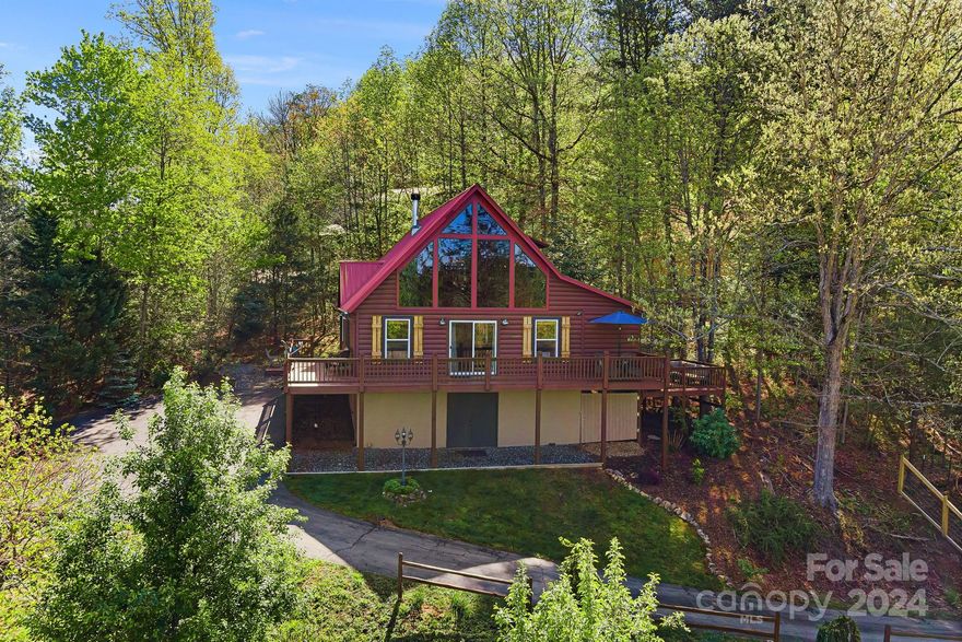 Charming cabin between Bryson City and Cherokee featuring a stunning living area showcasing a floor-to-ceiling stacked stone gas fireplace, hardwood floors and soaring vaulted ceiling. Large windows flood the space with natural light, enhancing the mountain views.The kitchen boasts granite countertops, central island w/gas cooktop, ample cabinet storage, cozy dining area and a convenient mudroom. The main level includes one bedroom and a versatile bonus room currently used as a bedroom, a full bath and laundry facilities. The upper level is a private sanctuary, offering a primary suite with a loft overlooking the living area, walk-in closet, and an ensuite bathroom. Outside enjoy the expansive wrap-around deck, secluded side porches, a fenced yard for pets, an EV charger, paved driveway, under-cabin storage, and an add'l storage shed.Currently a successful short-term rental and sold fully furnished, this cabin represents an excellent investment opportunity or peaceful mountain retreat.