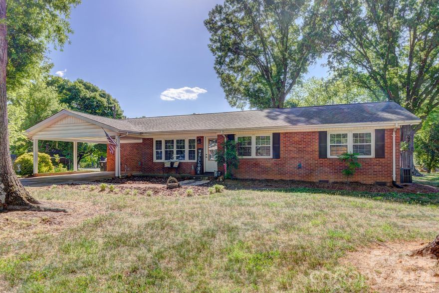 Very nice and tastefully updated brick ranch with more than six decades of single-family ownership tells the story of a well-kept, solidly constructed home that still has plenty of chapters left to write. Built in 1962 in the established and desirable Delview Acres community, this 3-bedroom, 2-bath home retains the bones of classic mid-century craftsmanship, with meaningful and modern updates layered over the years — including a brand-new natural-gas HVAC system installed in 2025.

Inside, hardwood floors run through the main living areas, anchored by a fireplace with gas logs that grounds the living room. The updated kitchen is the clear focal point of the interior — white cabinetry, a stone tile backsplash, stainless steel appliances (including a gas range), a dedicated pantry, and a centered island with bar seating combine to form a workspace that opens directly to the dining area through a wide pass-through. Crown molding carries through the dining room, which receives good natural light from a broad front-facing window and a decorative glass entry door. The primary bedroom is situated at one end of the home, with a full private bath, alongside two additional bedrooms. Both full baths have been updated with granite vanity tops and warm wood cabinetry. A dedicated laundry room with upper cabinetry and tile flooring rounds out the interior. The sunroom addition off the rear of the home is one of the standout spaces in the house — a vaulted ceiling with skylights brings natural light from above throughout the day, while windows along multiple walls keep the room bright at any hour. LVP flooring, counter space with a sink and cabinetry, and its own exterior entry make it a genuinely functional extension of the main living space rather than a seasonal afterthought.

Out back, a large wood deck steps down to a concrete patio and an open, tree-shaded yard with mature hardwoods providing a natural canopy. A portion of the deck is covered with a metal roof panel, creating a sheltered outdoor zone with room for seating and grilling. Toward the rear of the lot sits a nice, wired building with substantial workshop, rec room, or storage potential, with an attached enclosed shed. The attached two-car carport and concrete driveway handle covered parking directly off the front of the home. A separate adjacent lot of approximately 0.50 acres is available for purchase outside of this listing — interested buyers are encouraged to inquire for details.

A property with this kind of ownership continuity, lot size, and range of functional spaces is increasingly uncommon, and the potential to acquire additional acreage next door only adds to the long-term flexibility this address offers.