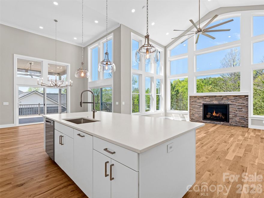 Newly completed, this Weaverville estate is defined by its 18-foot window-wall overlooking acres of forested creekside greenway, and centered upon a grand fireplace. This custom design showcases two vaulted primary suites, a mountain-view office or guest ensuite entered through French doors, expansive decks—both covered and open, and a chef’s kitchen grounded by its luxury island. A spacious laundry room connects to the lofted garage and RV bay, with an EV-ready charging location.

A dramatic open-air stair leads down to two distinct terrace-level wings. One wing offers a private guest retreat with bedroom, bath, living area, wet bar, and walk-out 500-square-foot patio. The second is a fully independent two-bed, one-bath suite with private exterior access, a dedicated driveway, kitchen, laundry, pantry, and living area.

Additional features include a 24 kW generator, 400-amp service panel, high-efficiency Trane heat pump with gas furnace on the main level, and dual-zone heat pump serving the terrace level. Built for HERO and Energy Star certifications.

Located in Greenwood Park alongside neighboring Reems Creek Village, this established community is known for custom homes, quiet streets, and sweeping mountain views—south and east to the Blue Ridge, west to Pisgah and the Smokies, and north to Hamburg Mountain. Convenient to Reems Creek Golf Club, downtown Weaverville, Asheville, the Blue Ridge Parkway, and the area’s upcoming hospital.

Open house Friday, Saturday and Sunday from 9AM to 4PM.