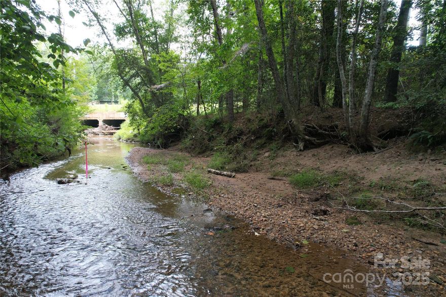This small acreage tract offers approximately 300± feet of frontage along Stafford Creek—a wide, flowing creek that leads to Lake Rhodhiss. Located inside the gated Waterfront Club community, this mostly timbered parcel combines natural beauty with exceptional access and convenience.
The topography is level allowing for easy access to a potential homesite.  Enjoy paved road entrance to the property off Scenic Lane, where public water is available, and a survey is already on file. Septic will be needed for development.
This is one of the limited creekfront tracts available within Waterfront Club, making it a rare blend of privacy, natural setting, and community lifestyle. As a property owner, you’ll have full access to all Waterfront Club amenities, including Dockside Park and Pavilion with Community Dock, Beachfront and Pool Pavilion, Kayak Launch, Walking Trails, and two gated entrances.
Set in the scenic Foothills of North Carolina, this property combines mountain charm with lake-access living—just a short drive to Hickory, Morganton, and Blowing Rock.