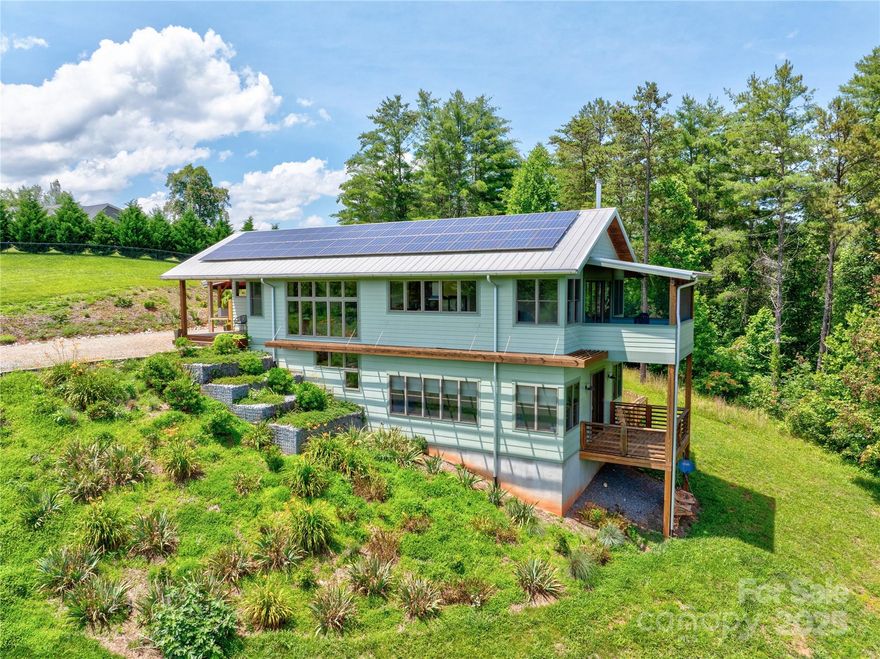 Art in Construction!
This magnificent custom green-built, net-zero home is a true work of art perched on 4.5 private acres w/southern exposure. Just 20 mins to Asheville, the home offers distant views of Mt Pisgah & the serenity of nature, w/ plenty of space to make it your own.  Designed w/ sustainability & comfort in mind, the home features a strategically placed stairwell along the South facing wall that collects passive solar heat. An interior Trombe wall at the stairwell serves as thermal mass, absorbing heat during the day & releasing it at night, also doubles as a living planter, bringing natural beauty indoors.
Rust-colored concrete floors are a stunning design element & function encompassing radiant floor heating on both levels, powered by an efficient electric system, adds comfort while keeping energy costs low. A 9.86 kW photovoltaic solar array on the south-facing roof supplies power for the HVAC & the home’s electrical needs.
This is sustainable living at its finest!