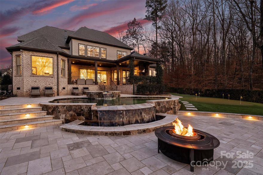 Exquisite custom estate in the sought-after Reserve at River Run Country Club. A double-door entry welcomes you to an elegant curved staircase, detailed dining room, and a tucked-away office that can serve as a bedroom with cathedral ceiling. The open-concept living area features a redesigned kitchen island, gas range, farmhouse sink, hidden push-through pantry, two dishwashers, and custom lighting. The primary suite is a luxurious retreat with a clawfoot tub, dual vanities, and an indulgent steam shower. Smart home technology includes a built-in security system, upgraded sound system, and CAT5E wiring. Ample storage includes a walk-in space above the three-car side-load garage. A panoramic sliding door opens to a covered patio with a grill and fireplace, overlooking the heated pool, spa, and private putting green. This serene lot backs to an HOA-owned wooded area and tree preserve, ensuring ultimate privacy. River Run offers premier golf, tennis, trails, and more in vibrant Davidson.