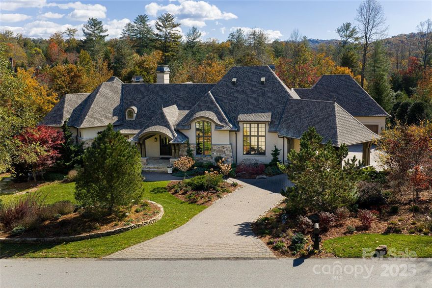 A striking architectural gem within Asheville’s coveted Ramble Biltmore Forest has officially entered at 10 Fairsted Drive,Designed by acclaimed architect Christopher Phelps, celebrated for crafting some of the Carolinas’ most notable luxury homes, the custom storybook residence was featured in Carolina Home + Garden for its fairytale charm and contemporary flair, seamlessly blending Old European Revival architecture with modern restraint to capture the essence of elevated mountain living.
Set amid professionally landscaped grounds, the porte-cochère and medallion-accented motor court, framed by native stone and stucco, create an exterior both grounded and poetic. Three stately chimneys and expansive terraces rise in harmony with the surrounding landscape.
Inside, 4,600 square feet of refined living space is defined by clean architectural lines, 22-foot vaulted ceilings with exposed beams and custom-stained white oak floors. The chef’s kitchen designed to pair commercial-grade appliances with custom cabinetry and Caesarstone surfaces, while artisan metalwork by Asheville artist Warren Perdue lends sculptural elegance to the formal dining room.
A private 1,100-square-foot guest suite on the lower level extends the home’s versatility with a full kitchen, dining area and home theater. Smart-home features, including two Tesla EV chargers and an integrated security system, enhance comfort and convenience throughout.
Crafted to complement its natural surroundings, the home’s outdoor spaces capture the quiet elegance of The Ramble at Biltmore Forest, featuring a screened pavilion, a stone fireplace, flagstone terraces and an expansive 25-person alfresco dining area. A lower paver terrace with a sculptural gas fire bowl and boulder seating creates an intimate setting amid the privacy of the wooded landscape, all overlooking the tranquil beauty of Longmeadow  Park. A one-of-a-kind estate.
*This home includes a 2nd Ramble lot purchased to secure their privacy - Green space, then added a side lot split with the neighbor, as shown on the ATTACHED PLAT.
Ramble Lifestyle LINKS can be found on the Feature Sheet to expedite the information you can share with your amazing buyers/clients. Call me for your private showing -