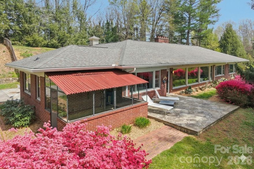 This masterfully engineered mid-century modern sanctuary offers the ultimate lifestyle with one-level living, zero-grade entry, and major peace-of-mind updates, including a new HVAC and new water heater. Designed by an engineer over five years to perfect its passive solar orientation, the home stays naturally cool in summer and warm in winter. The heart of the home is a sun-drenched living area where wall-to-wall glass frames the gardens, even casting a soft pink glow throughout the room when the azaleas bloom.

Sprawling across 3,000+ square feet, the layout features a 2023 designer kitchen with Caesarstone counters and integrated appliances—including cleverly concealed refrigerator and dishwasher. Pristine original hand-laid tile bathrooms preserve the home's vintage soul, while the 2.63-acre grounds offer ultimate privacy with minimal grass to manage.

The property includes a greenhouse with radiant heated floors and a massive open-concept studio that could serve as a rec room, gym, or creative workspace. Enjoy a quiet, intentional pace of life just 1.5 miles from downtown Marshall and a short drive to Asheville. Architectural gems this meticulously planned are a rare find; this is your chance to own a move-in-ready work of art.