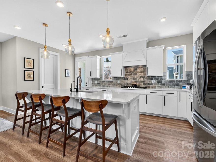 SLEEK, designer upgrades throughout this like new, END-unit townhome! Gorgeous white Chef's Kitchen with upgraded black hardware, upgraded glass & gold pendants, upgraded black faucet, an RO water filtration system, quartz countertops, tile backsplash, 5 burner gas cooktop, huge island w/ bar seating + walk-in pantry. Covered Balcony with ceiling fan off the Kitchen. Spacious Family Room with SUPER-sized ceiling fan with light. LVP flooring throughout main living areas and brand new designer carpet in Bedrooms and Loft. Main level features BR + Full Bath, drop zone with bench seating & storage shelf with hooks and garage access. The third floor features the Primary Bedroom with a walk-in closet with a barn door and metal storage shelving. The Primary Bath offers dual sinks, white cabinets w/upgraded black hardware & faucets, tiled walk-in shower, soaking tub, and designer glass lighting. Two additional Bedrooms on the third floor. All Bedrooms feature an upgraded ceiling fan with a light and shades. The Loft features a chic ceiling fan with surrounding light.  Hall Bath with upgraded hardware, faucets and lighting. Refrigerator, washer, dryer included!!  Oversized garage. Smart home system installed.  Situated within the University Research Park area, this location is fantastic with nearby shopping and dining amenities as well as walking and biking paths!