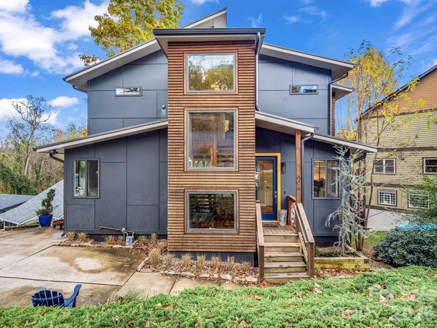 Incredible modern home in Asheville's River Arts District! Enjoy the best of Asheville living just a short walk to New Belgium Brewing! This is an ideal home for year-round living for buyers wanting minimal maintenance and yard upkeep. It's also perfect as a second/vacation home, as it has 3 primary suites (including one on the main level), making it just right for larger gatherings or extended family! The open floorplan and main level deck is perfect for entertaining or just enjoying a peaceful evening at home. From the living room, dining area, and decks, you can see the downtown Asheville skyline and the mountains beyond. The upper level has 2 massive primary suites with walk-in closets and beautiful bathrooms, as well as an office nook. The lower level has 2 more bedrooms, a bonus/TV room, full bath, and an unfinished space for storage (great for bikes, kayaks, and seasonal decor). The lower deck offers a second outdoor living area, and also has a hot tub! This quality built home has a Superior Wall precast concrete foundation, upgraded finishes throughout, and a location that can't be beat! Some furnishings negotiable.