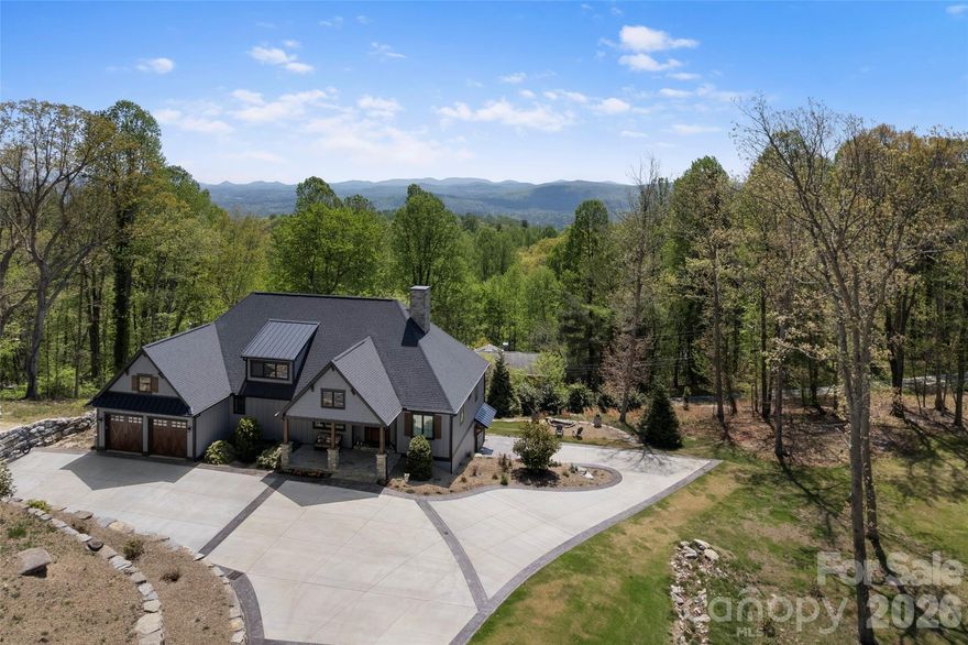 Set on over two private acres with breathtaking year-round mountain views, this custom-built residence in the sought-after Sky Village area of Laurel Park blends luxury, comfort, and versatility with two distinct living spaces. From the moment you arrive, a sense of tranquility sets in—this is more than a home, it’s a retreat. Inside, the living room features soaring vaulted ceilings and a striking stone fireplace, creating a warm, inviting atmosphere. The open-concept kitchen is thoughtfully designed with high-end appliances, ample workspace, and a generous pantry—ideal for both everyday living and entertaining. Expansive Marvin windows frame the surrounding landscape, filling the home with natural light and showcasing the views. A covered porch with its own fireplace extends the living space outdoors, offering a perfect setting for year-round enjoyment of the long-range mountain vistas. The terrace level adds flexibility with a spacious recreation room and kitchenette, along with a fully equipped private apartment featuring its own kitchen and laundry. Additional highlights include a two-car garage and whole-house generator. Located just minutes from Jump Off Rock and downtown Hendersonville, this property offers peaceful mountain living with convenient access to modern amenities.