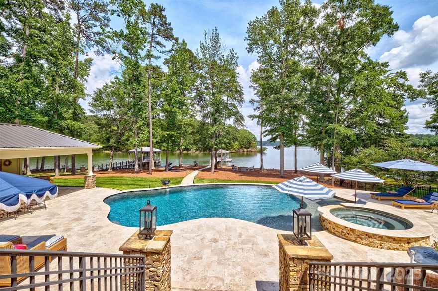 PRICE IMPROVEMENT! Welcome home to this amazing flat waterfront lot &magnificent custom home w/travertine saltwater pool that does not disappoint.There is huge cabana to enjoy the outdoor living w/bar/frig,bathroom,shower,mounted TV all connected to the pool area w/waterfall & sun ledges & built in umbrellas.Waterviews are expansive & wow sunsets.The yard also offers concrete walkways,fire pit area,kayak storage & floating dock w/ a lift and dockbox.The home offers many special details &extras. 5 bedrooms, 4 1/2 baths and 4750 sq ft. The elegant primary suite is on the main floor with 180' views when you open your eyes of the water. Large open kitchen w/oversized island,laundry/utility room w/ even more cabinets w granite ,wine frig,butler panty, great room & dining room. Upstairs is 4 bedrooms AND massive bonus room to entertain all.2 walk in storage/attic areas & 4 more storage nooks. BRAND NEW ROOF! Clover Schools!Easy commute to Charlotte. 1 acre lot & 140 feet of water frontage