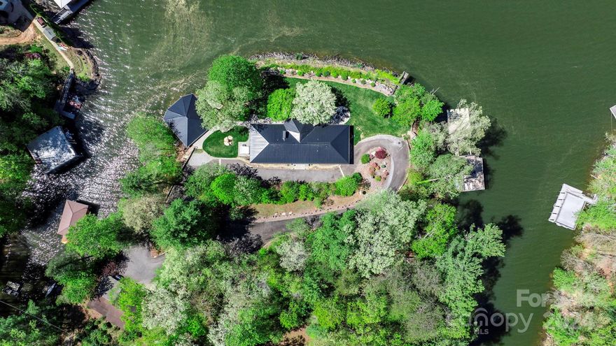 Modern mid-century one story design, renovated in 2020/2021, nestled on a peninsula at Lake James! Panoramic water views in the gated community of Lake View Hills Estates on a dockable lot, totaling 1.28 acres. The family room features a marble mosaic accented, wood burning fireplace & sliding glass doors leading out to a wrap-around Techo-Bloc patio w/5 person salt water hot tub & fire pit to enjoy year round. The chef inspired kitchen is equipped w/incredible backsplash, SS Appliances & expansive quartz island, perfect for socializing. Two spacious bedroom retreats on each side of the home, offer their bathrooms & lake views. At the water's edge, the boathouse is a two-in-one design w/lower level providing shelter to watercraft & 900 sqft above w/full bath & HVAC. A floating dock w/gangway attached to the fixed two-story dock w/covered single boat slip & Jet Ski ports. Cost effective front irrigation, 4 vehicle carport & circle drive.