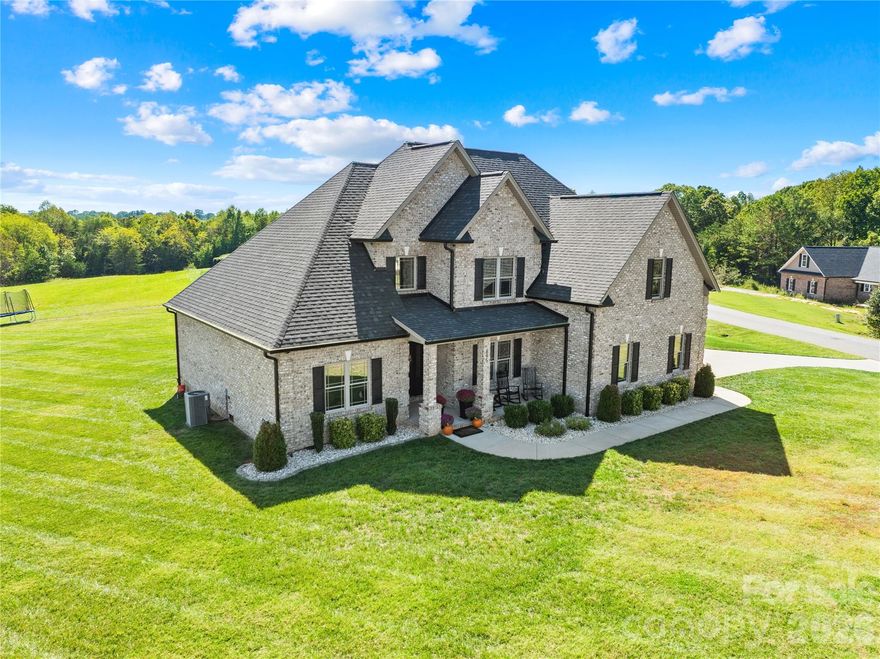 Don't just drive by and wonder... NOW is the time to come check out this next to new, custom-built full brick home offers 5 bedrooms, 3 full baths and timeless elegance throughout! If quality is what you are looking for, search no further! Step inside to find soaring ceilings, a grand foyer, and a striking floor-to-ceiling brick fireplace in the great room. The open-concept design flows seamlessly into the gourmet kitchen featuring custom cabinetry, stainless steel appliances, and a large center island perfect for gathering and entertaining. The main level showcases 9’ ceilings, gleaming hardwood floors throughout, and a luxurious primary suite with a spa-like ensuite highlighted by a gorgeous tile shower and soaking tub. A guest bedroom and full bath are located on the main level along with a formal dining room and laundry room. Upstairs, you’ll find 8’ ceilings, 3 additional bedrooms, and a full bath ideal for guests, office space, or a playroom. Thoughtful details include tinted privacy windows for energy efficiency and curb appeal that shines with a classic rocking chair front porch flanked by stately brick columns. Enjoy outdoor living on the spacious covered rear porch, complete with a built-in gas line for grilling. With nearly an acre of land, there’s ample room to design your dream backyard with plenty of space for a custom in-ground pool! Why wait to build when this home combines luxury, comfort, and endless potential all in one remarkable package! Enjoy the golf cart lifestyle cruising the neighborhood  or downtown Maiden for all the local festivals and parades! Just minutes from Denver, Hickory, Lincolnton, Maiden & Newton, an easy drive to Charlotte via Hwy 16, this location screams COUNTRY LIVING without giving up the convenience of nearby shopping, restaurants and hospitals. *PLEASE NOTE...The outdoor photos do reflect VIRTUALLY STAGED OPTIONS for landscaping and pool! Be sure to check out the video tour!