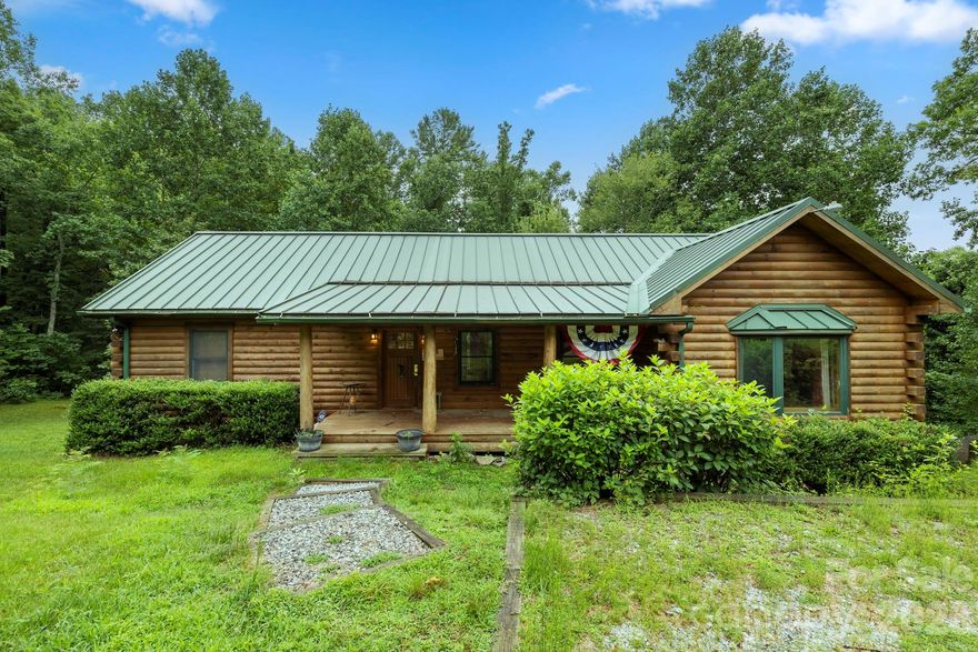 Fresh opportunity awakes this spring to scoop up a classic cabin on over 2 acres of wooded privacy!  This lovely home offers the perfect blend of rustic charm and modern comfort. Step inside and find open living areas with vaulted ceilings, tongue and groove finishes, and a welcoming cabin feel throughout. The spacious kitchen features high-quality cabinetry and beautiful granite countertops, ideal for entertaining. Enjoy the ease of one-level living with all bedrooms and key elements on the main floor.  A generously sized primary suite with a walk in closet and en-suite bath is tucked on one side of the floor plan, with two guest bedrooms, and another full bath on the other. The finished basement adds flexible space for guests, a game room, or family gatherings. A jumbo 2-car garage provides ample room for vehicles and storage. The cozy covered front porch and enormous rear deck offer great spaces for some R&R.  Situated in a peaceful, tranquil setting with easy access to downtown Saluda, this home is a serene retreat you’ll never want to leave.  Extra acreage possible if desired!