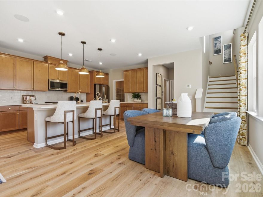 This end-unit, two-story home at Ellis Townes is thoughtfully positioned, offering a sense of privacy and a peaceful backdrop for everyday living. A fenced front yard and full-length driveway add convenience, while tree-lined views set the tone for relaxed mornings and easy outdoor living. Inside, the bright kitchen features white cabinetry, quartz countertops, additional cabinet storage, and a large island sink with a Delta Essa Touch faucet paired with a GE 30" slide-in electric range, all opening to flexible living space ideal for entertaining. A versatile loft provides room for a home office or creative retreat, while three bedrooms and two-and-a-half baths include a secondary bath with dual vanities and a spacious primary suite finished with warm cabinetry, creating a comfortable, design-forward retreat.