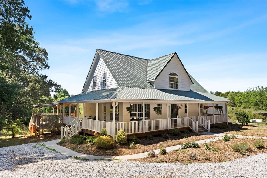 If you've been searching for land, space and a home that actually supports the life you want to live, this is where the search ends!

The long, private driveway is the first sign you've found something different. Before you fall in love with the inside, don't forget to enjoy everything the property has to offer outside. The fenced backyard for the dogs, the previously certified organic garden space just beyond the fence to start your homestead, the chicken coop and a separate grazing pasture off to the side, ready for animals whenever you are! Beautiful sunsets, wildlife, and wide open sky are part of the daily routine here. 4.59 acres. No HOA. No one telling you what to do with any of it.

As you head to the front door, the wrap-around porch sets the tone before you even step inside. Come inside and the first thing you notice is the fireplace. Floor-to-ceiling brick, anchoring an open concept living space. This isn't just a visual centerpiece. It's also part of the home's passive solar design, built on generational farming knowledge of harnessing sunlight to naturally heat and cool the home. The brick acts as thermal mass, absorbing heat during the day and releasing it at night. Those large rear windows give you a gorgeous view of the back of the property, but they're also another intentional layer of the passive solar design.

This is a fully custom home with so much character, and you feel it in every detail. Repurposed brick and old growth wood trim from a neighboring farmhouse built in 1860. Recycled antique doors with glass doorknobs.

The kitchen stands out with slate flooring, custom cabinets with under-cabinet lighting, and unique river rock cabinet pulls, small details that tell you someone lovingly thought through every choice in this home. Right off the kitchen is your floor to ceiling custom pantry with handmade shelves & brackets for your heavier canning equipment and well as shorter shelves on sides to store all your canned food from your garden! A homesteaders dream! Right off the primary bedroom, you'll find a huge laundry area with tons of built in storage. Move into the large primary suite and you'll find the show stopper: the standalone soaking tub. Upstairs, you find 2 rooms sharing a large full bath that's already pre-plumbed for a second sink vanity if you choose. Use these rooms as bedrooms, a home office, homeschool room, or whatever works for how you actually live.

Head downstairs through the beautiful antique door to the walkout basement (also known as your unlimited potential). You're looking at approx. 1,200 square feet of unfinished space with another floor-to-ceiling brick fireplace. It's already plumbed and ready for a half bath. Workshop. Gym. Guest suite. Storage. Second living area. Another office. Your call.

This is Mt. Ulla. A tight knit, agriculture-rooted community in western Rowan County where cows graze on one side and an organic produce farm sits on the other. Country roads are still shared with tractors, neighbors know each other by name, and the community still gets together for annual tractor rides and corn shuckings. It sits right on the county line outside Mooresville, which means Lake Norman, shopping, dining, and the interstate are all just minutes away. You get the privacy and space of true rural living with a short drive to anything you need!