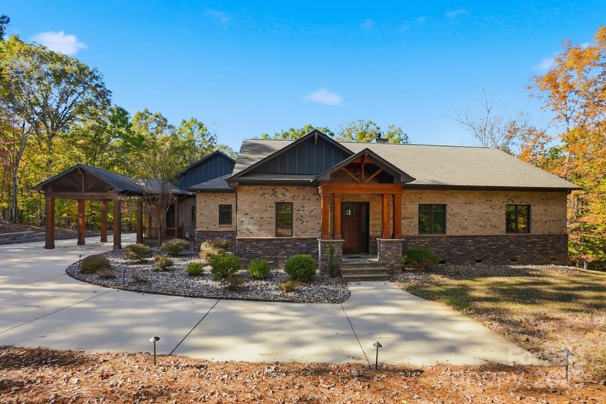 FIBER COMING TO THE COMMUNITY! Modern Craftsman Ranch with Mountain Lodge influences on 2.87 private Acres in gated Saratoga Woods! Experience refined living in this exceptional one-story all-brick ranch, perfectly set on 2.87 private acres within Waxhaw’s exclusive gated Saratoga Woods community. Offering approximately 4,400 square feet, 5 bedrooms, and 4.5 baths, this residence blends timeless craftsmanship, smart technology, and serene privacy—just minutes from shopping, dining, and South Charlotte conveniences. Inside, 10-foot ceilings, 8-foot doors, and White Oak hardwood floors with natural stain create an open, elegant flow. The chef’s kitchen impresses with quartz countertops, 6-burner grill top and downdraft range hood, dual ovens (top convection/microwave combo, lower convection), built-in wine cooler, and ultra-low-micron water filtration for the refrigerator. Custom organization includes cutlery and pot inserts, spice pull-outs, lazy susans, and a dedicated pantry with built-in freezer. Soft-close cabinetry is enhanced by a built-in mixer riser and touch-activated garbage drawer. The owner’s suite serves as a private retreat with dual custom closets and a spa-style bath featuring a soaking tub, oversized walk-in shower, and dual-bowl vanity. Two bedrooms share a Jack-and-Jill bath with dual vanities and large walk-in shower, while the fourth & fifth bedrooms enjoy their own en-suite baths. Multiple home-office locations provide flexibility for remote work or creative use. Fresh paint and new carpet add a crisp, renewed look throughout. Premium Windsor casement windows with internal mesh screens invite fresh air, while a 12-foot collapsible Windsor sliding door opens to the covered rear patio for effortless indoor-outdoor living. The home features extensive spray-foam insulation, an encapsulated, humidity-controlled crawl space, and a Home Team Taexx pest control system. The oversized 3-car garage offers 24-foot depth, extra-high ceilings (ideal for a car lift), ultra-quiet LiftMaster side-mount openers, built-in cabinetry and drawers, a stainless industrial sink, pre-wiring for 220-volt power, and multiple 15- and 20-amp outlets. The UV-resistant polyaspartic epoxy floor adds a polished, durable finish. A porte-cochere on the side of the home provides covered guest parking and a private entry through the large mudroom, ensuring convenience and versatility for family or visitors. Smart systems and efficiency upgrades include a Generac 26 kW whole-house generator (installed 2024) tied to a 1,000-gallon underground propane tank, capable of supporting the home for up to two weeks. The system is maintenance-free, under warranty, and remotely monitored. Connectivity is robust with Starlink satellite internet, a Ubiquiti whole-house network, and integrated home automation controlling lighting, energy management, and exterior illumination. Most rooms feature smart dimmers, while driveway and patio lights are fully automated. The media room is pre-wired with surround sound and built-in speakers, and every room includes wired connectivity for wall-mounted TVs and streaming. Outdoor living shines with a covered back patio featuring ceiling fans, built-in speakers, pre-wiring for a TV, and pre-plumbing for an outdoor kitchen or bar. A comprehensive water-management system includes screened gutters that never clog, underground piping to divert runoff away from the home, and engineered drainage to keep the driveway dry. Additional storage includes a rear attached storage room and a separate shed tucked into the wooded backyard for lawn equipment or seasonal items. Set within a quiet, gated enclave, this property delivers the ultimate blend of luxury, technology, functionality, and privacy—a meticulously designed ranch offering unmatched comfort and convenience in one of Waxhaw’s most desirable communities.