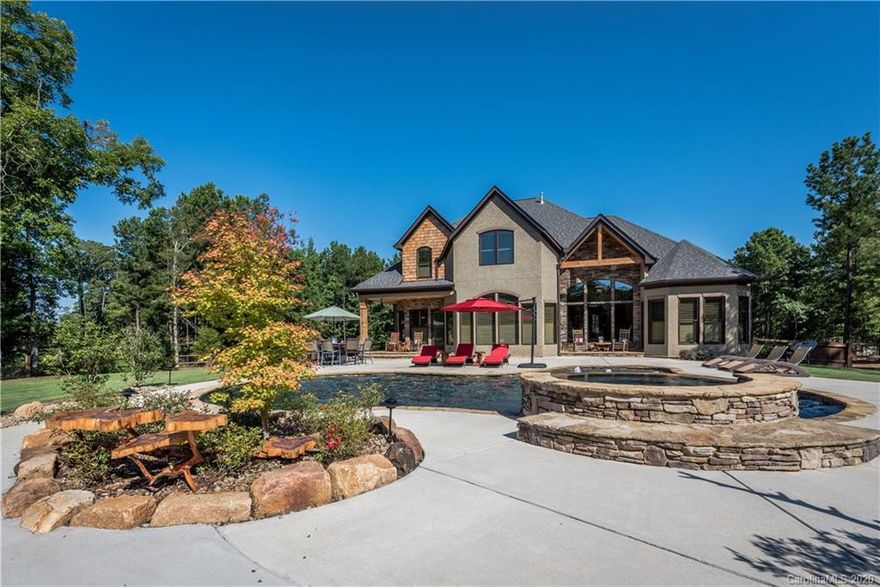 Be prepared to be impressed from the beginning with this creatively designed home.
The stone and stucco exterior invites you into an even more stunning and memorable property to only experience in person to truly appreciate it. All hardwood floors with stone and pine accents create the feel of something special.  The great room with rock fireplace and a view to the pool, that looks like it came from a magazine, will leave you wanting more.  Gathering around the the gourmet kitchen will be a regular occurrence to look forward to. After a long day a retreat to the master bedroom or relaxing shower will be just what you imagined.  The lagoon style pool in a word is amazing.  Your only limitation is your imagination. The pool house is a one of a kind with a mix of granite, pine and corrugated tin accents. Atmosphere is perfect whether it is game night or an extension of entertaining at your pool party.  The new high school is only 2.7 miles away!