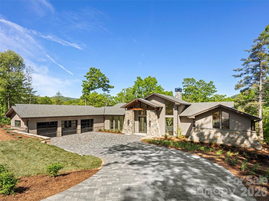 Nestled within the prestigious gates of The Cliffs at Walnut Cove, this masterfully designed mountain transitional estate offers a rare combination of high-altitude privacy and sophisticated luxury. Occupying a prime position close to a gate, this residence provides access to the Blue Ridge Parkway and the vibrant cultural hub of Asheville. Currently under construction with a scheduled completion in the summer of 2026, this brand-new residence allows homeowners to be the first to enjoy its bespoke finishes and modern amenities. Residents of this exclusive community enjoy an unparalleled lifestyle centered around a world-class wellness center, Jack Nicklaus Signature golf course, and the social elegance of the award-winning clubhouse and "The Tavern." The architectural narrative of the home begins with a striking exterior of natural stone and timber, leading into an expansive interior of meticulously crafted living space. The main level is anchored by a breathtaking great room where floor-to-ceiling windows frame long-range mountain vistas, seamlessly connecting the indoors to a sprawling screened porch and an open-air deck equipped with a majestic stone fireplace. At the heart of the home, a gourmet kitchen features a massive island, custom cabinetry, and professional-grade appliances, flowing effortlessly into a sun-drenched dining area. The primary wing on the main floor serves as a private retreat, boasting a vaulted owner’s suite and a spa-like bath with a freestanding soaking tub and a massive glass-enclosed rain shower.  The terrace level is a tour de force of entertainment, thoughtfully designed for grand-scale social gatherings. This level features a massive game room anchored by a large, custom-crafted bar, providing the ultimate setting for hosting friends or relaxing after a day on the course. Thoughtful design continues throughout the residence with high-end finishes including wide-plank oak flooring, designer lighting, and modern cable-rail staircases. The versatile floor plan includes a sophisticated home office and multiple guest suites with private baths. Beyond the glass, the outdoor living spaces are second to none, highlighted by a lower-level stone terrace perfect for evening gatherings under the stars. Completing this exceptional offering is an oversized three-car garage, a whole house generator, and an elevator that services both levels, ensuring this home remains a lifetime legacy property in Western North Carolina's most coveted community.