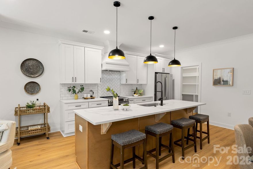 Discover elevated modern living in this END UNIT brand-new townhome - where thoughtful design meets uncompromising style in Charlotte’s most connected pocket. Step through the sleek glass front door into a bright, welcoming entry featuring custom drop-zone built-ins: open shelving, bench seating, and hooks for effortless daily organization. The open concept main level is built for modern, seamless living and effortless entertaining. The chef-inspired kitchen dazzles with quartz countertops, a striking herringbone tile backsplash, custom range hood, premium stainless steel appliances, & an oversized island. Plus a full walk-in pantry with built-in wood shelving. Cozy up by the fireplace with oak mantle in the inviting living area—perfect for gatherings year-round. Upstairs, the oversized primary suite is your private oasis: accent wall, expansive walk-in closet with custom organizers, and a spa-like ensuite boasting dual vanities with gold fixtures, a luxurious floating soaking tub, and an oversized tiled shower with bench. Bonus: direct access from the primary closet to the full-size laundry room for ultimate convenience. Two flexible secondary bedrooms suit guests, a home office, or family needs. No carpet anywhere—clean, modern luxury throughout. Location is everything: Just a short drive to top-rated Oaklawn Language Academy (Spanish immersion magnet), 4 minutes to the vibrant Camp North End (art, food halls, breweries), 2 minutes to Johnson C. Smith University, and quick hops to the Gold Line, Uptown Charlotte, and I-277. Contemporary flair. Premium upgrades. Unrivaled convenience. This isn’t just a home—it’s your next chapter. This home also qualifies for 100% financing with no PMI and up to $20,000 in lender assistance for closing costs, rate buy-down, or loan amount reduction. In addition, the Builder is offering up to $10,000 in closing cost assistance with the use of the preferred lender! Schedule your tour today!