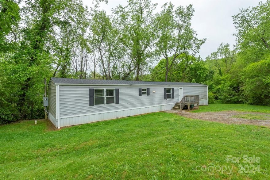 Discover this single-wide mobile home on a permanent foundation in Fairview, just a short 15-minute drive from downtown Asheville. This home features 2 cozy bedrooms, plus an additional room with a closet and windows, ideal for an office or bonus room. The primary bedroom includes a spacious walk-in closet and a private en suite bath. This layout offers a dedicated dining area, a practical laundry room, and a welcoming living room, making it perfect for comfortable living. Outside, enjoy a small stream that flows at the back of the property, providing a serene outdoor space. This home has proven to be a reliable long-term rental over the past 12 months, generating an income of $1,500-$1,800 per month. Recent updates, include a new roof and hot water heater that were installed in April of 2024. Please note that this home is owned by a licensed North Carolina broker. Don't miss the opportunity to own this charming and conveniently located home!