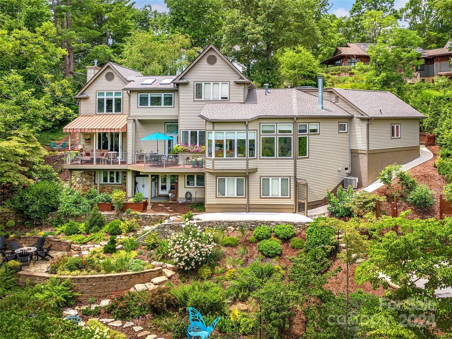 PRICED BELOW BANK APPRAISAL!  Coveted North Asheville hilltop living with serene mountain views from almost every room in this impressive Mark Sinsky design home.  Enjoy coffee together or a glass of wine on the private terrace overlooking impressive perennial gardens and the nearby mountains of the Grove Park neighborhoods.  Rare, elevated hilltop N. AVL location, just over a good stones throw away from the historic Omni Grove Park Inn, and minutes from everything you could need including the heart of downtown Asheville. Bright open kitchen and light filled rooms with mountain views, open to the rear terrace. Two living rooms where the fireplaces burn offering warmth on these cold winter days. You will love shooting hoops or practicing pickleball on your own new fenced-in basketball court.  Expansive lower level with full bath opens to gardens w/views, organic raised beds for gardening and a place to sit and relax with friends!  This is in-town mountain living at it's best!