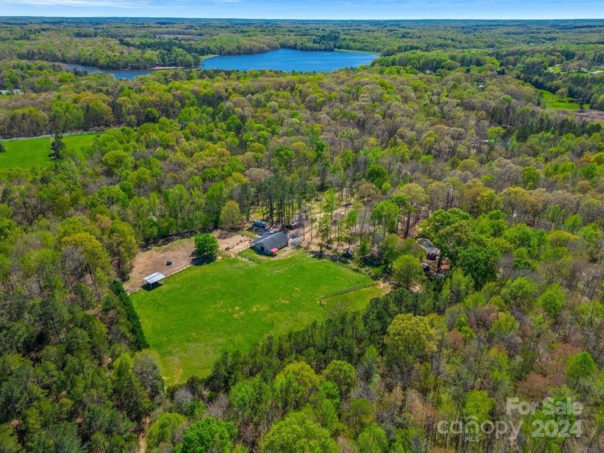 This extraordinary property is a true equestrian paradise, featuring multiple fenced pastures and a 5-stall barn. With 4 bedrooms, 3 full baths, and a versatile bonus room, this residence seamlessly blends elegance with comfort. The grand two-story great room, anchored by a magnificent stone fireplace, serves as the heart of the home. An additional entertainment area, complete with a built-in bar and adorned with exquisite 100-year-old handscraped barnwood wainscoting, radiates rustic charm. The gourmet kitchen is a chef's dream, showcasing gleaming granite countertops, high-end stainless steel appliances, & a custom copper farm sink. Upstairs, you'll find the secondary bedrooms, including a second primary suite. Outside is your own private oasis, w/ an in-ground pool, hot tub, and a custom masonry fireplace. One of the property’s standout features is its enviable location, just a minute's trot from Cane Creek Park, offering an unparalleled blend of luxury and convenience.