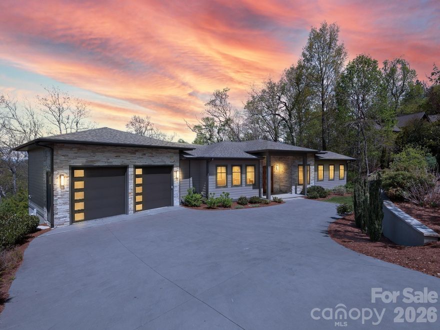 Perched within the prestigious Reynolds Mountain community, this exceptional one-owner contemporary estate offers sweeping mountain vistas just minutes, approximately 3 miles, from the refined culture, dining, and arts of downtown Asheville.  Designed to capture both light and landscape, the residence showcases superior views from nearly every room. The grand great room is anchored by a dramatic stacked stone fireplace and flows effortlessly into an elegant dining area and a chef-inspired kitchen appointed with stainless steel appliances and a statement island.  The main-level primary suite is a serene sanctuary, featuring a spa-quality bath with radiant heat flooring, an expansive walk-in shower and private access to a full-length deck, perfectly positioned for morning sunrises and tranquil evening retreats with vino and a view. The lower-level daylight walk-out basement features expansive covered decking that captures stunning long-range mountain views and exceptional privacy. This level is further enhanced by a second stacked stone fireplace, an open area curated for entertaining, including wet bar, wine nook, and three beautifully appointed guest suites, with all full baths all boasting radiant heat flooring.  Additionally, for refined elegance and ultimate convenience, this exceptional residence is thoughtfully appointed with a private elevator, offering seamless access to every level of the home.  Extensive recent enhancements reflect a commitment to quality and design, including fresh interior painting, newly stained decks, and thoughtfully updated landscaping. Custom window treatments throughout, featuring privacy coverings, tailored valances, and Roman shades, all add a refined finishing touch.  Modern living is seamlessly integrated with advanced systems, including a radon mitigation system, enhanced gutter drainage, and a comprehensive smart home security suite with cameras, full alarm integration, and electric keyless entry.  Set within one of Asheville’s most coveted luxury enclaves, featuring an urban village just moments away, this residence offers an unparalleled blend of elevated mountain living and effortless access to city sophistication.  Welcome home to your sanctuary tucked within Reynolds Mountain.