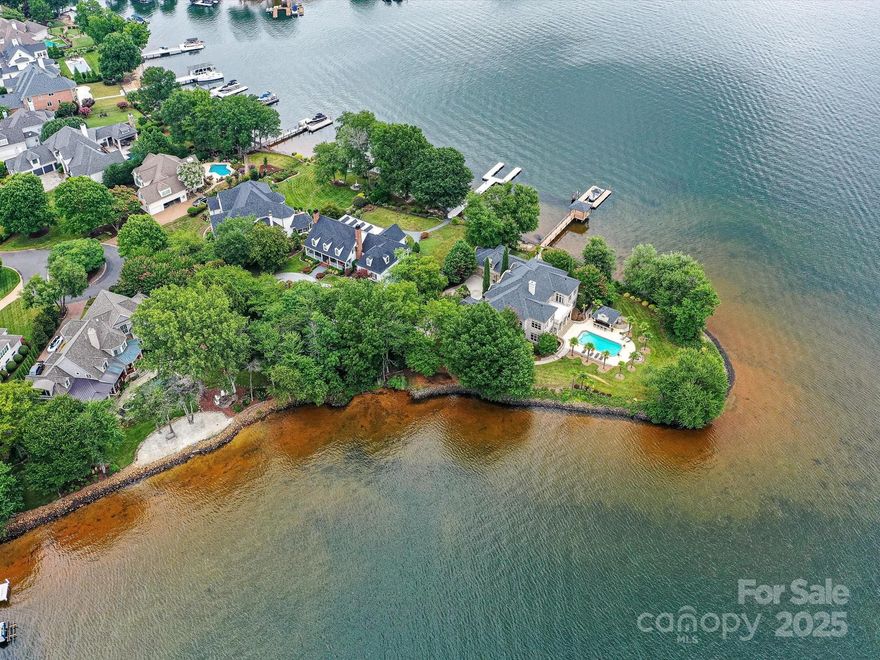 Located on a private, gated point lot in the prestigious Peninsula, this breathtaking waterfront estate offers nearly 650 feet of shoreline with sweeping, unobstructed views from every room. Surrounded by Lake Norman on three sides, the residence is a rare opportunity for ultimate privacy and grandeur. Step inside to soaring ceilings, a dramatic curved staircase, and timeless European-inspired architecture. Walls of windows flood the main living areas with natural light, while exquisite detailing, hand-painted murals, and custom millwork create a one-of-a-kind interior. The chef’s kitchen features ornate cabinetry, a large island, and lake views from nearly every angle. The outdoor living is truly resort-style with a large pool, outdoor kitchen, covered patio, and fireplace—all set against the backdrop of long-range water views. A private dock with covered sitting area completes this extraordinary offering. Truly designed for grand entertaining, lakeside serenity, unforgettable sunsets