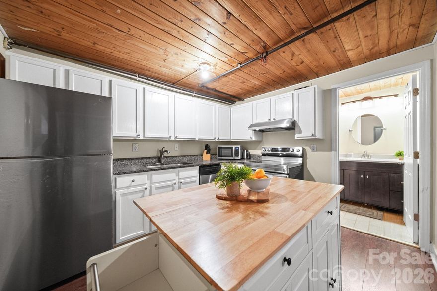 Rare 2-bedroom, 2-story loft condo for sale in Charlotte, NC — 858 sq ft of original exposed brick, soaring wood-plank ceilings, and arched factory windows inside the Historic Hoskins Mill, established 1904. This is not new construction. This is the real thing.

Welcome to Unit 129 at FoxRidge Lofts — a meticulously converted textile mill in Charlotte’s storied Hoskins neighborhood where industrial history meets modern living. Original wooden support columns, hand-hewn timber beams, and deeply textured brick walls create a space that no new build can replicate. This is the kind of place that draws people in and doesn’t let go.

The entry level opens into a sun-drenched living room framed by arched factory windows and deeply textured brick. A generous dining area connects seamlessly to a thoughtfully designed kitchen featuring white shaker cabinetry, rich granite countertops, stainless steel appliances, and room for an butcher block island — designed for the cook who understands that ambiance is half the meal. The main-floor bedroom provides drama with soaring ceilings and windows, and the full bath is finished with an espresso-toned vanity and stone countertop.

Ascend the dramatic dark-stained staircase to the upper loft — a sprawling 19’ x 17’ bedroom that feels like a private sanctuary. Exposed timber beams, original brick, and wooden ceilings make this space unlike anything else in Charlotte. It’s the bedroom you’ll never want to leave.

Beyond your unit, the building itself is an experience. Enjoy a grand community room with soaring timber ceilings and original columns, a free on-site laundry facility with no coins required, secured access, and ample parking. Google Fiber installation is projected for spring 2026, and the HOA has completed significant capital improvements in recent years, including a new fire safety system, LED lighting, parking lot upgrades, grant-funded landscaping, and a commissioned neighborhood mural. The FoxRidge Lofts community is owner-managed, engaged, and actively investing in its future. This is a place with a story — and space for yours.