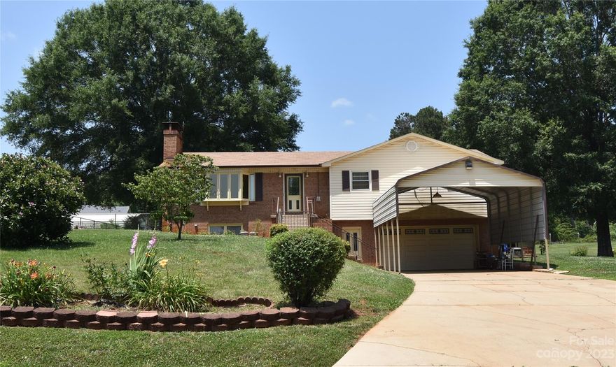 You will enjoy this home for many years to come. This 3 Bedroom, 2-bathroom One Story home with basement located in the Bethlehem area of Alexander County. This property features an open living room, dining and kitchen concept. Hardwood and carpet flooring. Lots of Kitchen cabinet space with an eat-in breakfast bar. Two wood burning fireplaces. Primary bedroom has a full bathroom. Basement has a large family room with Kitchen sink and place for a stove and refrigerator. Dining room has sliding glass doors that open to a nice sunroom that can be used for many purposes. The family room in the basement has a wood burning fireplace as well as an outside entrance. This space could easily be used for a separate in-law suite. Two car garage with large RV carport for parking. The backyard is fenced in, and the entire property has lots for perennial blooming flowers, bushes, trees and grape vines. Nice out building for storage. Such a great value. Come and see today.