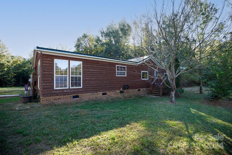 This charming 3-bedroom, 2-bath home offers serene country living on 6.53 acres at the end of a peaceful cul-de-sac in the desirable Lewisville school district. Enjoy the beauty of nature while still having plenty of storage with a 2-car detached garage and 3 sheds, one wired for electricity. The home features a newer metal roof, an HVAC system replaced in 2022, and a whole-house generator that just needs servicing to be fully operational. The spacious kitchen boasts a huge work island with an exhaust hood, breakfast bar, and ample cabinet space. A large living room and a cozy family room with a gas-log fireplace provide ideal spaces for relaxation and gatherings. Fiber-ready with TruVista, this country retreat also includes a side covered porch, newer well bladder, and water softener, making it the perfect blend of comfort and rural charm.