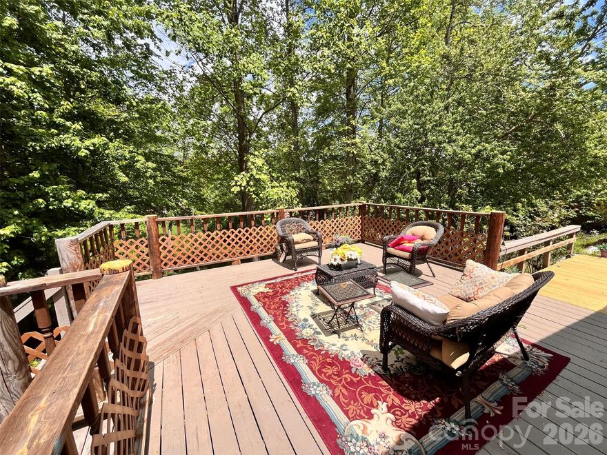 Charming country setting with one level living sitting up on the lot with great privacy.  Spacious home with two large living areas and open concept layout.  Split bedroom plan with Primary BR on one side and secondary bedrooms on other.  Huge kitchen offers abundant countertop space leading into den with gas log fireplace.  Completely updated guest bath with walk in shower.  Enjoy the large covered porch on summer days or the deck on the rear that spans the length of the entire house.  More than 1,800 s.f. of living space, all on one level!  New roof (December 2025) by Balkan Roofing.  Large recently completed detached double carport tall enough for parking an RV.  Down below the house near the street is a parking pad for a 5th wheel or additional guest parking if desired.  The community is a quiet neighborhood with excellent proximity to Asheville.  Generator and detached storage building conveys.  POA dues INCLUDE water from community system.