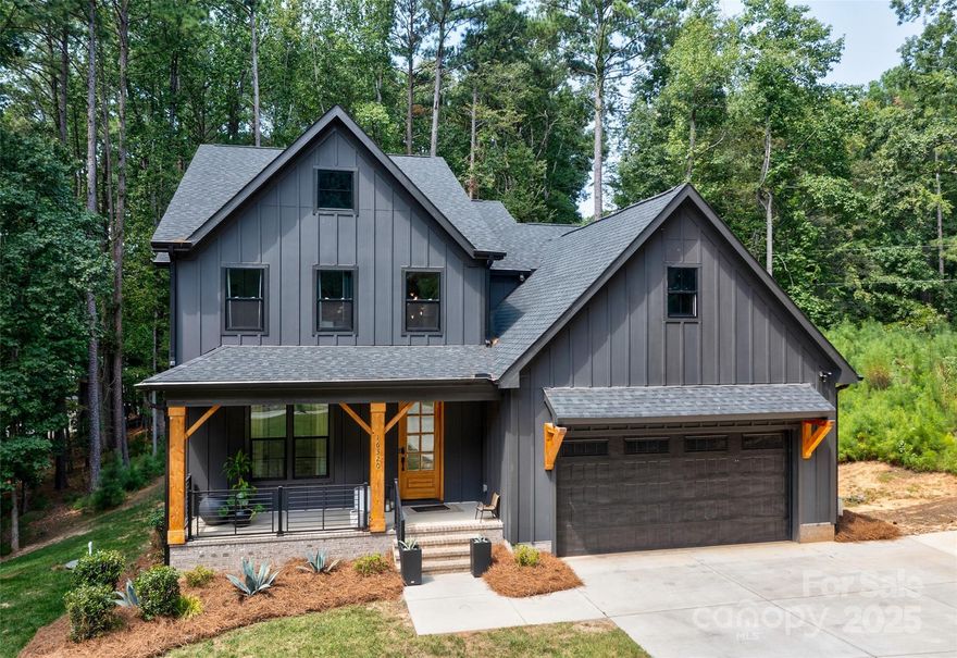 Luxury contemporary/farmhouse style at its finest. Situated on a large 1.75-acre wooded lot in the Rivers Edge community, this property is an ideal choice for those seeking a sleek, contemporary home. The custom-designed home plays with the contrasts of warm wood and dark gray paneling, creating an eye-catching entryway into this home. A private glass door study sits just off the grand entry foyer. The gourmet kitchen features ample white cabinetry, an oversized kitchen island with a single-bay sink, and ample seating space. A gas cooktop with stainless steel exhaust hood, wall oven, and custom pantry make preparing meals a joy. The open dining area flows seamlessly into the great room. Just outside the dining area is the covered deck, accented by a wood-paneled ceiling, overlooking the extended paver patio and serene wooded backyard. Truly an outdoor living paradise. The luxury primary suite has a spa-like bath with a free-standing glass-enclosed shower, dual vanities, and an ample walk-in closet. Upstairs, a second private office provides flexible space. Three spacious bedrooms and a barn door-enclosed bonus room provide ample space for the family and guests. Bedroom 2 features a hall bath, and bedrooms 3 and 4 share a Jack-and-Jill bath. This home also comes with an EV charger. Oversized garage and walk in crawl space provide lots of storage space. The community of Rivers Edge borders Lake Wylie, and is situated across the street from over 200 acres of conservancy land. Enjoy the beauties of nature and modern conveniences in this one-of-a-kind home.