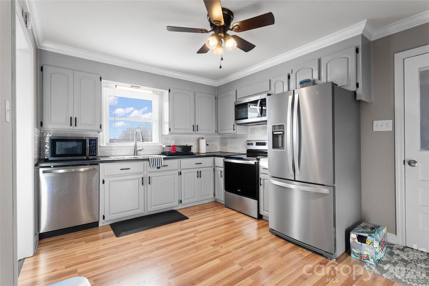 Charming full-brick ranch home featuring beautiful crown molding, chair rail, and beadboard accents throughout. A spacious living room welcomes you just off the foyer, creating a warm and inviting entry, while the dining room flows seamlessly into the country kitchen. The kitchen is equipped with stainless steel appliances, tile countertops, a tile backsplash, a new dishwasher, and plenty of cabinets for storage. Ceiling fans are installed in all rooms except the dining room. This meticulously maintained home showcases gleaming hardwood and LVP flooring throughout. A large laundry room offers added convenience and leads to a side exterior door. The side fenced yard is perfect for pets or outdoor enjoyment. Both bathrooms have been tastefully remodeled. Recent updates include new windows, new gutters (2024), new ductwork (2025), and a whole-home water filtration system installed in the crawl space (2024). A 20x20 metal detached garage built in 2024 provides excellent storage or workspace. Enjoy relaxing or entertaining on the back deck while taking in the beautiful spring weather.