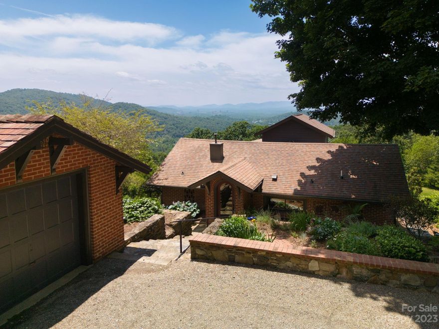 Rare opportunity: 3 acre family compound on an incredible site. 3 private dwellings open to panoramic yr-round views of DT Asheville & the Blue Ridge Mtns beyond. Original stone & brick, timber beam ceilings, wormy chestnut, cedar & oak details create unique charm. The main house includes a large primary w/adjoining library, a guest room w/deck access & 2 bonus rooms suitable for office or play. The 2nd dwelling awaits through a walk-thru stunning pergola. This 1 BR home is completely updated. The kitchen/living area opens onto a deck creating tranquil outdoor space. A stroll around 1 of the 2 garages brings you to the 3rd dwelling (also completely updated). Large windows showcase a lovely deck w/sunken spa. This home includes an open kitchen, dining & living area, 1 BR & glass block bath. A bucolic stone waterfall, stream & fishpond enhance the serene setting. Prime location, 3 gorgeous dwellings, beautiful gardens & wildflower meadows work together to create a feeling of enchantment.