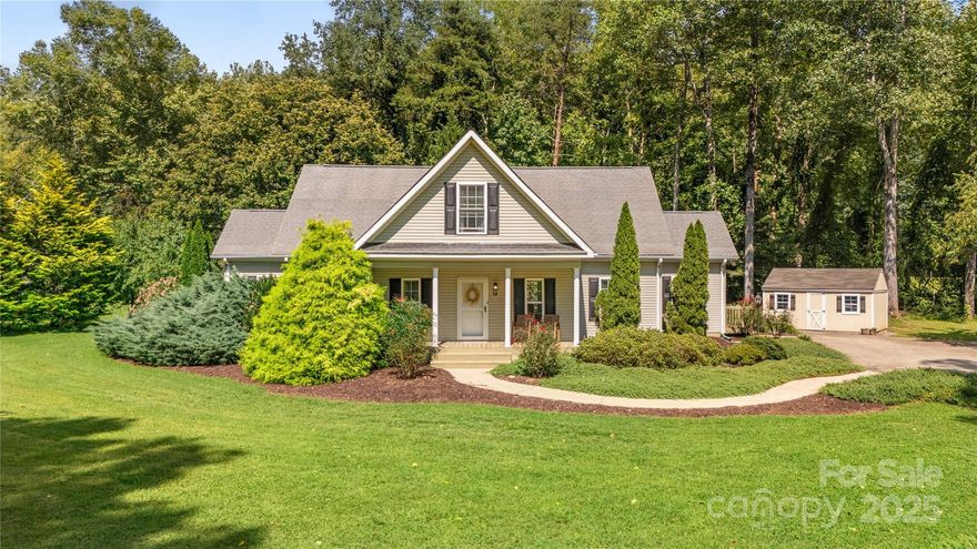 Welcome to 19 Lynnbrook Way in Columbus, NC. This inviting home is perfectly situated in the heart of the Thermal Belt, offering easy access to Landrum, Hendersonville, Tryon, and Spartanburg. Set on a private 1.1-acre lot, the property is surrounded by mature landscaping and bordered by the softly flowing Skyuka Creek. A long, curved concrete driveway leads to the home, which makes a striking impression from the road.
A covered rocking chair front porch creates a warm welcome, enhanced by beautiful plantings of junipers, golden mops, roses, and mature trees that provide both shade and privacy. Step inside to a tiled foyer with accent wall and enjoy 9-foot ceilings throughout the main level. The open floor plan features a large living room that flows into the kitchen and dining area. An arched opening adds character and charm, while the kitchen showcases a detailed coffered-style ceiling, long breakfast bar, and stainless steel appliances.
The main-level primary suite includes a sleek barn door with obscure glass, another detailed accent wall, a walk-in closet, and a spa-like bath with quartz countertops, dual sinks, soaking tub, and separate shower. A second bedroom with walk-in closet and a remodeled full bath with quartz counters and tile flooring are also found on the main level, along with a walk-in laundry room where the washer and dryer remain.
Upstairs, a spacious third bedroom and full bath with tiled shower are complemented by a flexible sitting area—ideal for an office, workout space, or reading nook—as well as a massive walk-in closet and generous walk-in attic for storage.
Outdoor living is just as impressive with a huge rear deck that’s perfect for entertaining. The backyard is level and versatile, offering plenty of options for gardening, play, or simply enjoying the serene creekside setting.
Practical updates include four mini-split HVAC units installed in 2023–24, remodeled bathrooms, and crawl space encapsulation. With its combination of privacy, modern updates, and peaceful natural surroundings, this property is a rare find in Polk County.