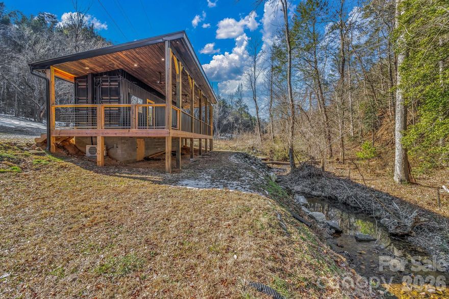 Welcome to this thoughtfully designed custom built container home offering modern efficiency and peaceful surroundings on .94 acres overlooking a beautiful creek. Fully built out and move-in ready, this unique property features a full kitchen, full bathroom, and private bedroom — maximizing every inch of space with smart design and quality finishes.

The kitchen is equipped with premium Big Chill appliances including an induction range, refrigerator, and freezer, blending style and performance in a compact footprint. Large windows invite natural light and bring the outdoors in, creating a bright and inviting atmosphere.

One of the standout features is the expansive 500 sq ft covered wrap around porch overlooking the creek — the perfect place to relax, entertain, or simply enjoy the soothing sound of flowing water year-round. This generous outdoor living space nearly doubles the functional footprint of the home and creates an incredible indoor-outdoor lifestyle.

Whether you’re looking for a turnkey short-term rental opportunity or a private mountain escape to unplug and enjoy the peace and quiet, this property offers incredible flexibility. Located just 10 minutes from downtown Hot Springs, you’ll have easy access to hiking trails, local shopping, great dining, and the area’s famous natural hot springs, all while being within an hour’s drive to larger cities like Asheville, NC and Knoxville, TN where you can enjoy even more dining, music and brewery options. 

Small footprint. Big experience. Rare opportunity.