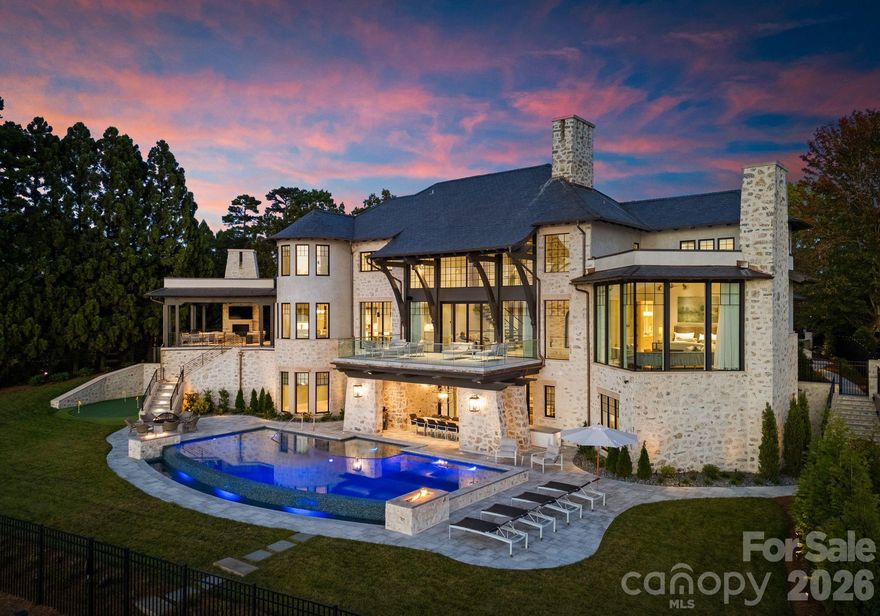 Experience a level of lakefront living where architecture, setting, and design exist in effortless harmony. Set along the shores of Lake Norman, this meticulously crafted estate captures long-range, year-round water views and a sense of quiet grandeur from the moment of arrival.

A dramatic two-story foyer unfolds into a grand salon, where walls of glass and fold-away doors open to expansive terraces, blending indoor and outdoor living. Light moves throughout, highlighting refined finishes and thoughtfully curated spaces.

At the heart of the home, a chef’s kitchen of exceptional scale features dual islands, a fully appointed scullery, and integrated appliances—designed for both gathering and precision. A covered lakeside terrace extends just beyond, complete with a fireplace, ceiling-mounted heaters, and an outdoor kitchen with Wolf grilling.

The main level is anchored by a private primary suite, thoughtfully positioned as a true retreat, offering serene lake views and a spa-inspired bath with elevated finishes and a sense of quiet separation from the rest of the home. Additional bedroom suites are thoughtfully arranged across all levels, including a main-level guest suite, a lake-level suite, and three expansive upper-level bedrooms—each designed with the scale and comfort of a private retreat, featuring walk-in closets and ensuite baths. Laundry on every level and elevator access throughout further enhance everyday ease.

The lake level is designed for both relaxation and recreation, featuring a full kitchen, golf simulator, fitness studio, sauna, and wine cellar.

Outdoors, a resort-style setting unfolds with an infinity-edge pool and spa, fire features, and multiple gathering spaces oriented toward the water. A private dock with dual slips and personal watercraft lifts provides immediate access to the lake.

Enhanced by Control4 smart home technology, the residence offers a seamless blend of sophistication and modern convenience. Offered fully furnished with interiors curated by David Smith Interiors, along with a pontoon boat and two PWCs. Opportunity to acquire membership to The Peninsula Club further elevates the lifestyle.