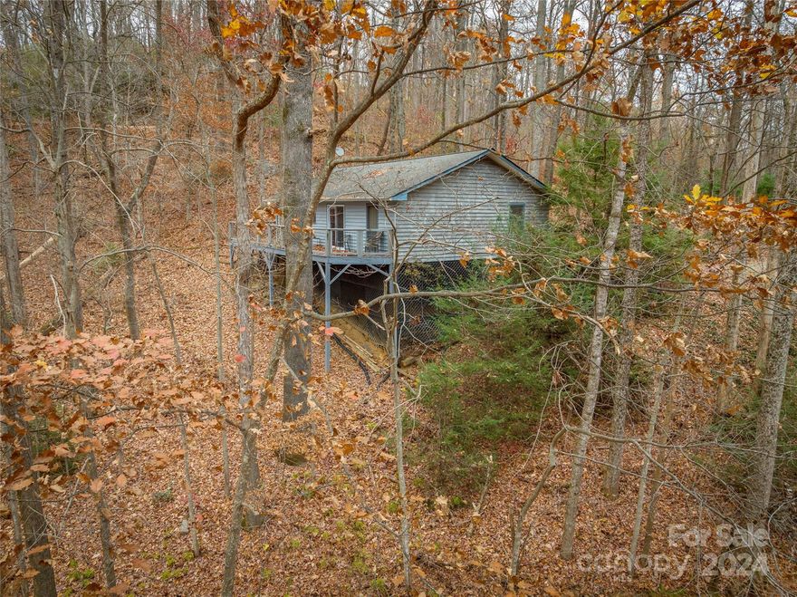 Experience mountain living at its finest with breathtaking long-range views and a cozy home to call your own. This home features two spacious bedrooms, two baths, and hardwood floors and walls that imbue the space with a cabin-like ambiance. Nestled on 4.95 acres of wooded land, you have the opportunity to wander down to the property's edge, where native plants, hardwood trees, and a gentle stream await. Savor a cup of coffee on your screened porch while observing wildlife meandering through the woods. The open floor plan concept is perfect for entertaining guests. This home is ideal as a year-round residence or a mountain retreat. It's conveniently located near Pearson Falls, hiking trails, fishing spots, and the historic Main Street of Saluda.