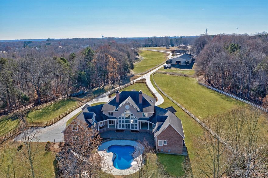 Animal Sanctuary, Equestrian Estate, Event Venue, Family Compound, endless possibilities. Desirable Mooresville schools & Davidson address. Gated entrance opens to fenced lined paved drive which takes you past the farm amenities, including 2 bed/2 bath guest house, world class 10 stall barn, equipment bldg & large indoor arena.  A circular driveway & impressive entrance to double front doors opening to 2 story foyer w/sightlines to great room & pool. The custom wall of windows bring the outdoors in.  Open floor plan w/kitchen & dining room overlooking the GR. Home designed w/two wings creating a courtyard pool area. Main floor primary suite houses a flex room, large bedroom & spa bath w/whirlpool tub, 2 granite vanities, custom built-ins & two large walk-in closets. 2nd floor true to life movie theater & game room both offer wet bars. 1 ensuite guest room w/access to 2nd floor balcony overlooking the farm. Enjoy trails, shuffleboard, horseshoes & disc golf. Detailed brochure available
