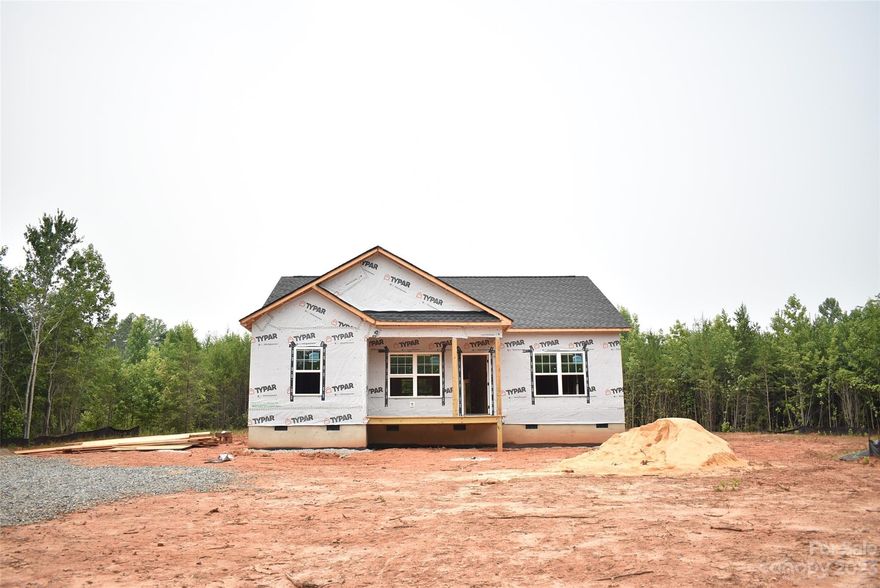 Newly constructed home available soon in the Clover area! This single story floor plan is located in a quiet, rural area on a low-traffic road. The 1443 sq ft home features a granite countertop kitchen with white shaker cabinets and a spacious walk-in pantry. The open floor plan connects the kitchen and dining area to the spacious living room. Off of the dining area is a comfortable covered back porch; perfect for a private afternoon retreat. The primary bedroom features a large walk-in closet and private bathroom, also with granite countertops. An enclosed laundry room adjoins the kitchen and dining area. Stylish exterior with vertical board and batten siding on the front. Private well and septic system. Energy efficient heat pump with high (14 Seer) efficiency rating. Driveway and parking pad will be concrete.