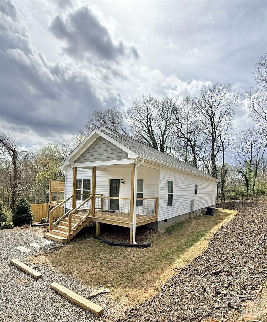 Tucked away on a private lot in the growing Candler area just minutes from Asheville, this single-level new construction home offers the perfect blend of comfort, style, and low-maintenance living. Designed with an open, airy layout and filled with natural light, the home feels calm, welcoming, and easy to live in. The kitchen features granite countertops, a farmhouse sink, and a seamless flow into the main living space—ideal for everyday living or gathering with friends and family. The spacious primary suite includes a large bedroom, generous closets, and a beautifully tiled walk-in shower. Enjoy the convenience of one-level living with durable, modern finishes and blinds throughout. Step outside to a private deck overlooking a peaceful wooded setting—perfect for relaxing after a long day. A rare opportunity to enjoy new construction, privacy, and convenience at an attainable price.