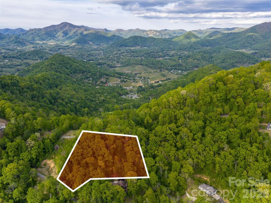 Discover the perfect canvas for your mountain dream home on this stunning 3+ acre lot in the highly sought-after Junaluska Highlands, a prestigious gated community nestled in the heart of Western North Carolina’s Blue Ridge Mountains. Offering breathtaking long-range mountain views that stretch across rolling ridges and misty valleys, this wooded parcel is ideally positioned with a gentle southern exposure—perfect for maximizing natural sunlight, passive solar benefits, and year-round scenic enjoyment. Mature hardwoods and native flora frame the property, providing privacy and a serene, natural setting while allowing you to selectively trim for even more dramatic vistas. Wide, paved roads with gentle access lead directly to the site, and underground utilities ensure a clean, uncluttered build. City water and Spectrum high-speed internet are already available, Septic system needed, simplifying construction and modern living. Junaluska Highlands is known for its beautiful custom homes and peaceful, upscale atmosphere, where neighbors value quality and tranquility. Just minutes from charming downtown Waynesville, you’ll enjoy boutique shops, farm-to-table restaurants, breweries, and vibrant community events. Asheville’s dynamic arts scene, airport, and world-class amenities are only 25 minutes away, while Maggie Valley and the Great Smoky Mountains National Park are within easy reach for hiking, skiing, and outdoor adventures. This rare opportunity combines privacy, convenience, and unparalleled natural beauty. Whether you envision a luxurious primary residence or a scenic mountain getaway, this lot delivers the foundation for a lifetime of inspiration. Don’t miss your chance to claim this slice of North Carolina mountain paradise.