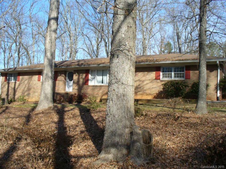 Solid brick ranch nestled on 3.43 wooded acres backing up to public park. Homes features formal areas, , kitchen and  breakfast area, den with fireplace and extra large utility room. Home has attached 2 car garage and detached 2 car garage with workshop and additional carport. City location and convenience  with county feel. Roof only 1 year old HVAC (heat pump) 2 years old.